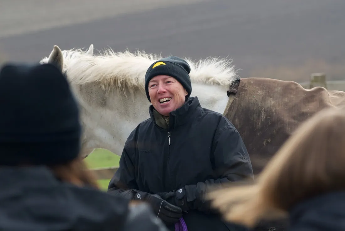 A coach in a woolly hat talking with riders during a clinic